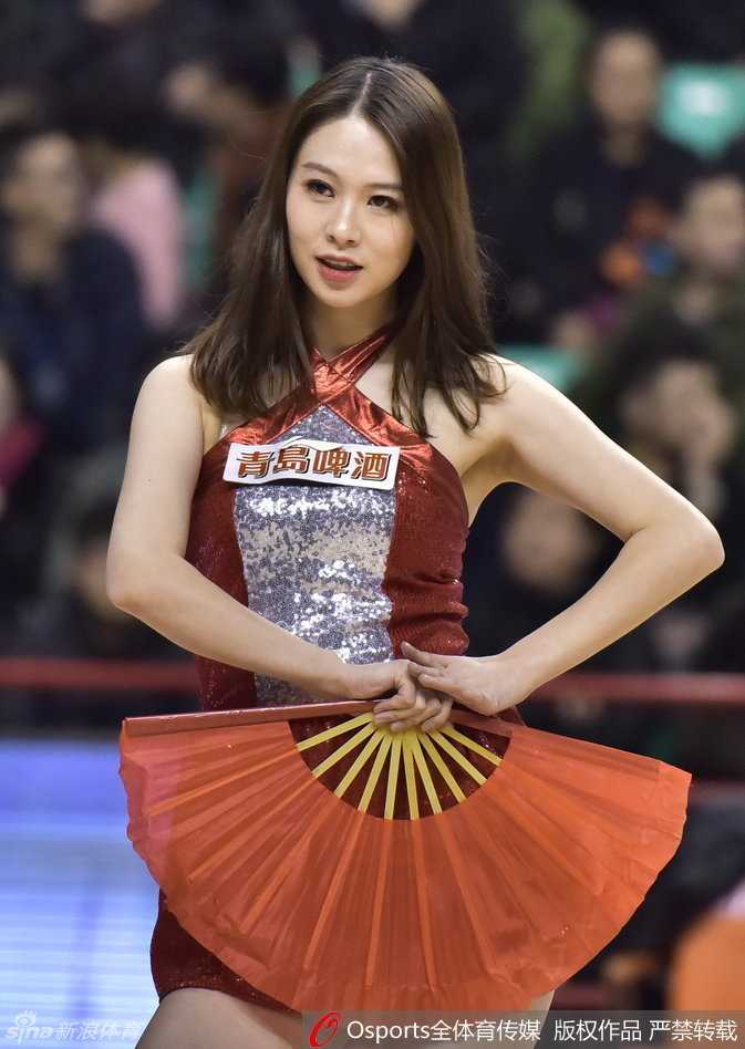 赛场灯光下，一位篮球宝贝自信地甩动秀发，眼神坚定地目视前方，背后的巨大篮球海报映衬出她此刻的主角光环。