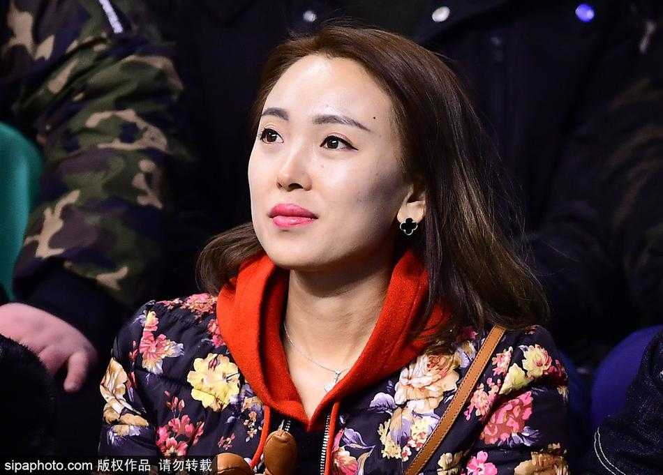 中场休息时，一位长发披肩的美女球迷回眸一笑，身后是正在热身的球员和热闹的看台，她的笑容仿佛拥有能让人忘却比赛压力的魔力。