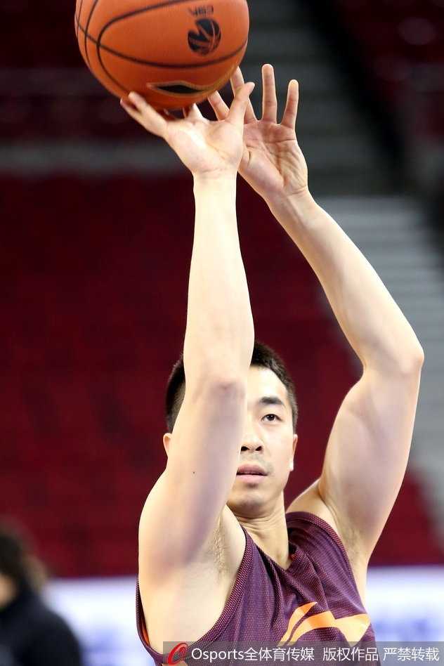 北京男篮另一名球员刘晓宇在训练中全神贯注，他双手持球，准备进行下一步的传球练习，神情严肃而专注，背后是其他正在热身的队友。