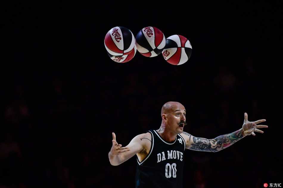 表演者正与场边小观众进行亲密互动，他将篮球轻轻递出，眼神中充满鼓励，孩子们脸上洋溢着惊喜的笑容，现场气氛温馨而热烈。