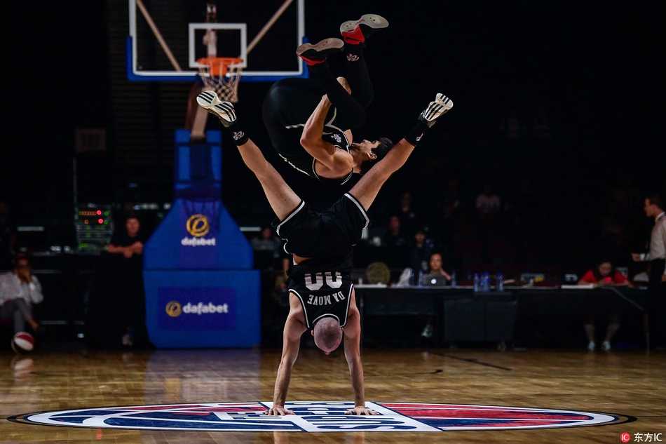 表演者身体舒展，眼神专注，篮球在他胯下划出一道优美的弧线，精准地飞向另一只手的掌控范围，充满了动感与韵律美。