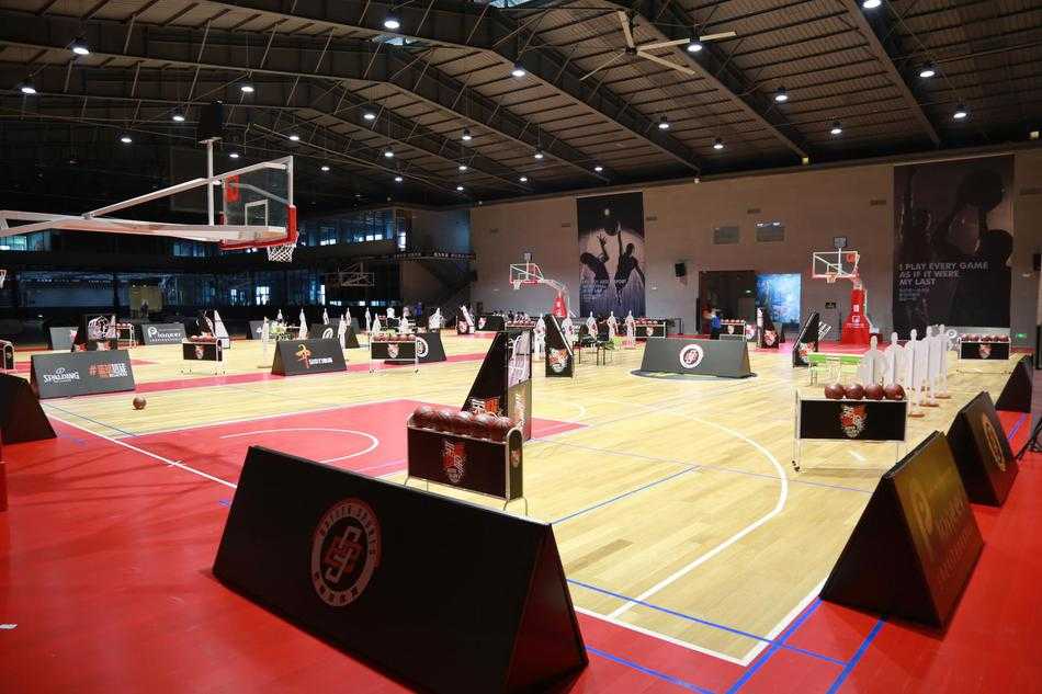 篮球名宿巴特尔身着黑色T恤，俯身与一位小球员击掌，他宽厚的肩膀像一座山，脸上却是慈父般的笑容，仿佛在说“年轻人，继续拼”。