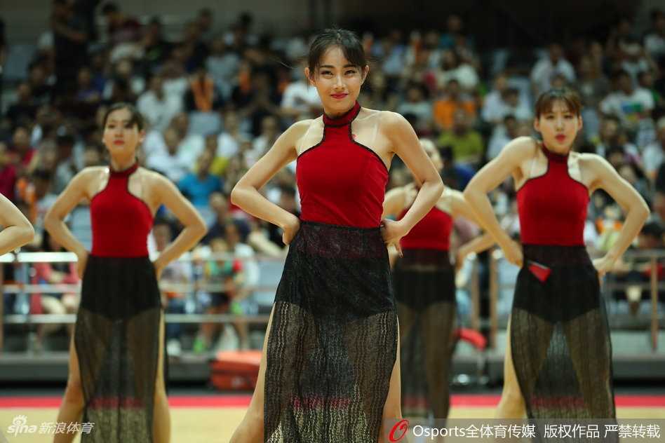 队员高抬腿动作瞬间，红纱裙角飞扬，露出修长美腿，笑容灿烂充满活力