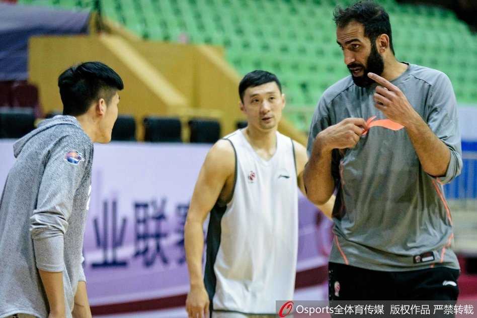 外援与队友在战术板上聚精会神，主教练手持战术笔比比划划，球员们时而点头，时而用眼神交流，仿佛在无声中达成了战斗的共识。