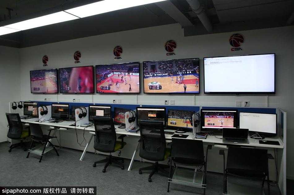 明亮整洁的CBA视频回放中心工作大厅内，一整面墙的监视器阵列正实时播放着不同场次的比赛画面，科技感十足。