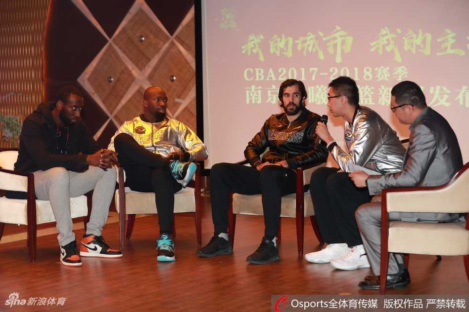 赵柏清手持队旗站在舞台中央，五彩的礼花从天而降洒落在他的西装肩上，他仰头看向空中的礼花，嘴角露出自信的微笑，身后的队友们都在鼓掌庆祝。