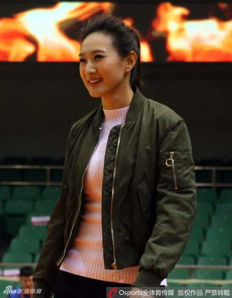 一笑一颦间透露出职业的自信，她站在篮架后方的摄影席上，宛如喧嚣场馆中一抹沉静而亮眼的色彩。
