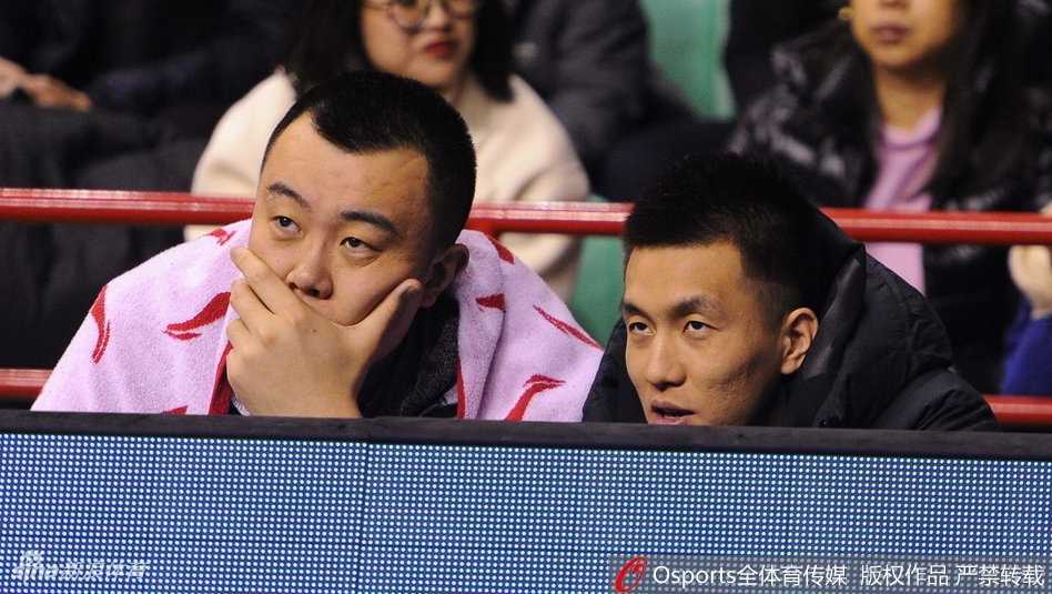 郭艾伦身穿着训练服，脸上洋溢着轻松的笑容，与队友韩德君交流着场上的局势，享受这段难得的场边休息时光。