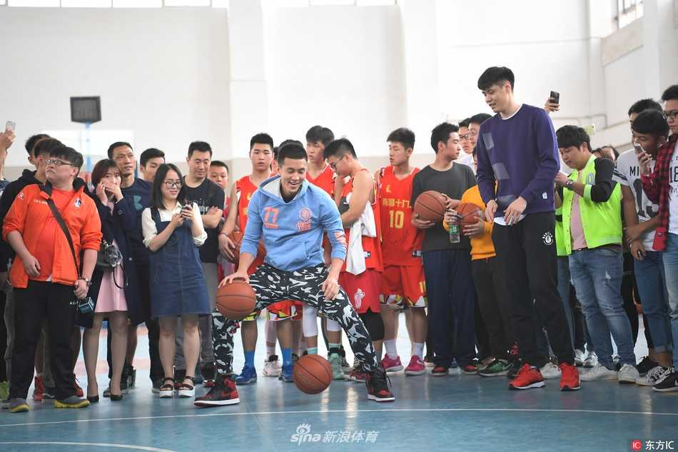 郭艾伦弯下腰，在一名穿着校服的小球迷递来的篮球上认真地签下自己的名字，小球迷则紧张又期待地盯着笔尖。