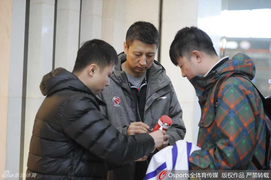 主教练郭士强被几位老球迷围住，他双手递回签好名的战术本，眼角的笑纹透露出对这份支持的感动
