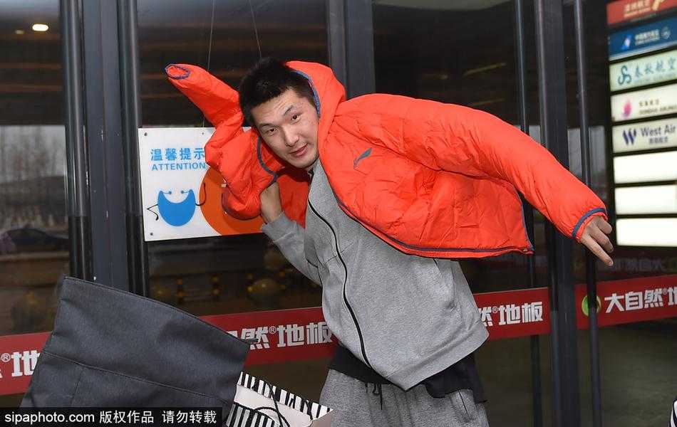 心情大好的郭艾伦侧身倚靠在栏杆旁，手中握着球迷递来的签名笔，正低头认真地在一个篮球上签下自己的名字，周围是无数双期待与喜悦的眼睛。