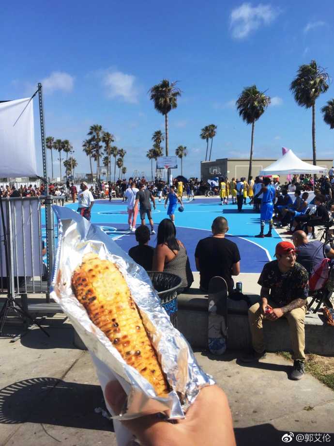 黄昏的海滩边，郭艾伦与一群街头篮球手围在一起，他手里还攥着没吃完的烤苞米，完全融入了这片自由而热烈的篮球氛围中。