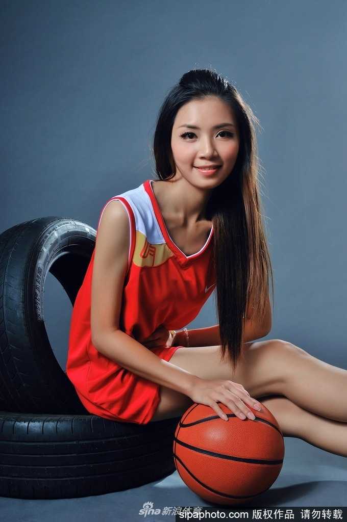 钟苑庄篮球宝贝写真 动感光影间尽展活力美型 钟苑庄侧身站立,双手抱球高举过头,身体曲线在球场光线下显得健美而修长