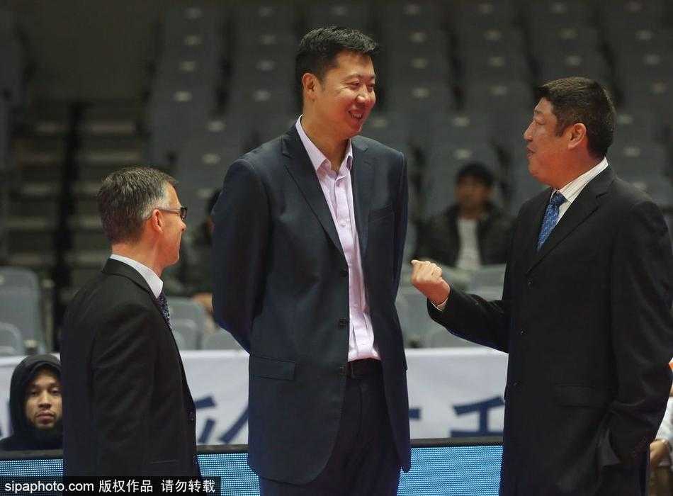 赛前热身区域，王治郅与江苏同曦队的一名年轻球员击掌问候，脸上洋溢着温暖而谦逊的笑容，毫无传奇球星的架子。