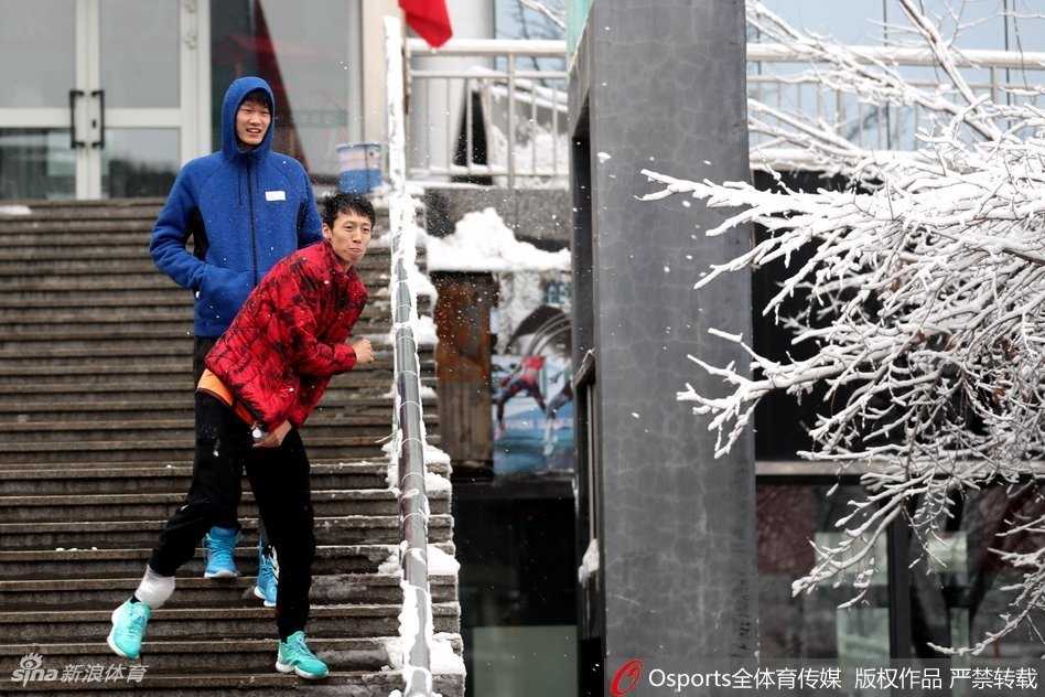 银装素裹的备战:广厦男篮乌鲁木齐雪中行迹 广厦球员在乌鲁木齐雪地中漫步,一行人在雪地上留下深浅不一的脚印,背景是冬日里静谧的城市景色。