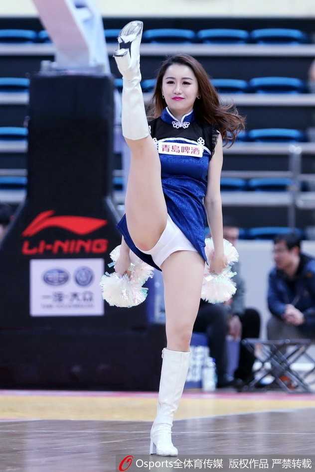 青岛篮球宝贝寒冬热舞燃爆赛场,演绎CBA别样激情 一位戴着白色毛球发饰的篮球宝贝双手叉腰侧身站立,紧身表演服勾勒出纤细的腰肢,她凝视镜头的眼神既甜美又充满自信,极具感染力