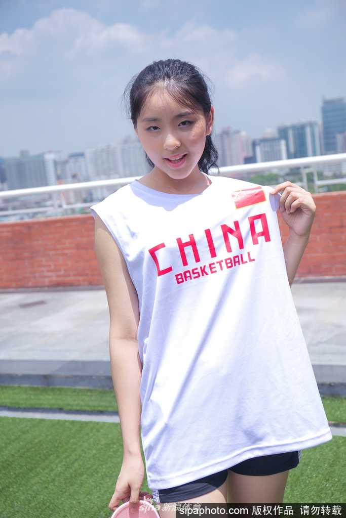 这位篮球宝贝展现了柔美的一面，她身着一字肩上衣，在窗前静静沉思，窗外的光线勾勒出她精致的侧颜，画面静谧而美好，仿佛在积蓄赛场上的能量。