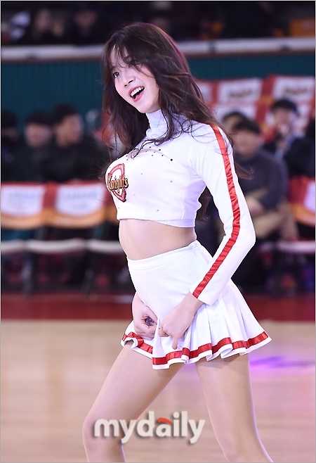 一位籃球寶貝紮起俏皮的雙馬尾，身著亮黃色緊身舞衣，在場邊隨著音樂節奏扭動纖細腰肢，眼神中閃爍著自信的光芒。