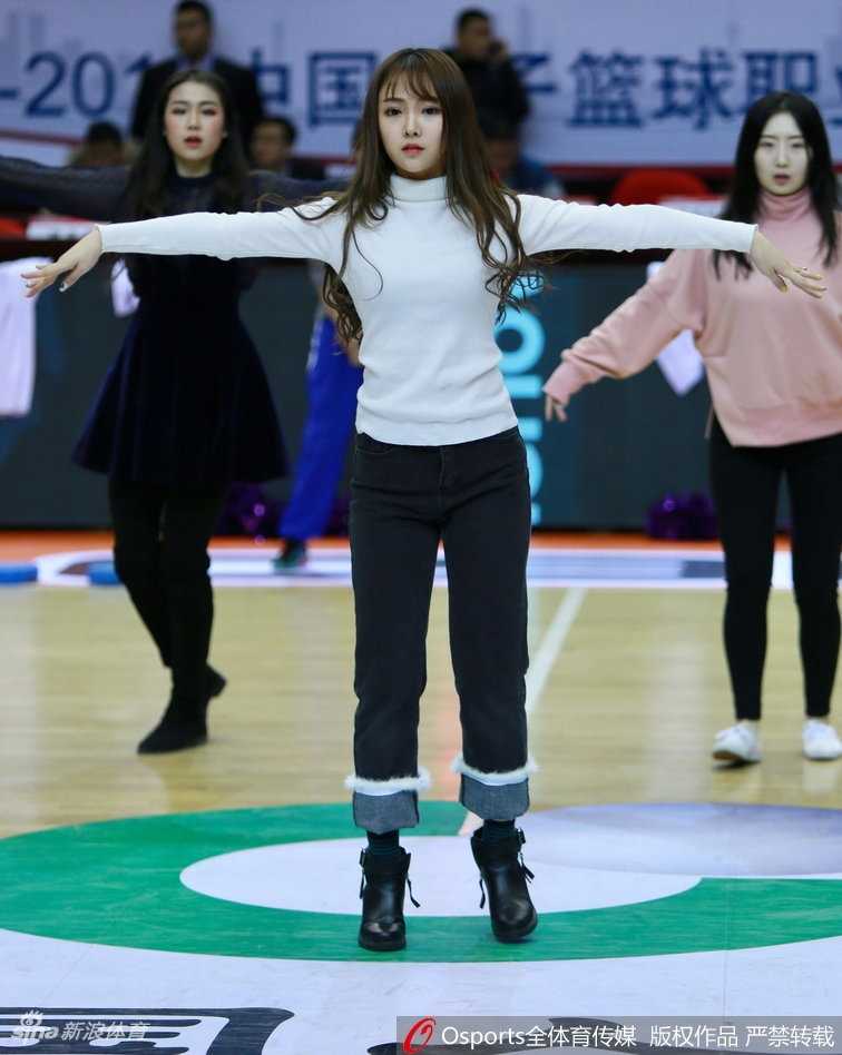 这位舞者正在场边压腿拉伸，侧颜线条优美，虽然神情严肃认真，但脸颊上的一抹绯红却泄露了她因备战而微微发烫的脸颊，显得格外惹人怜爱。