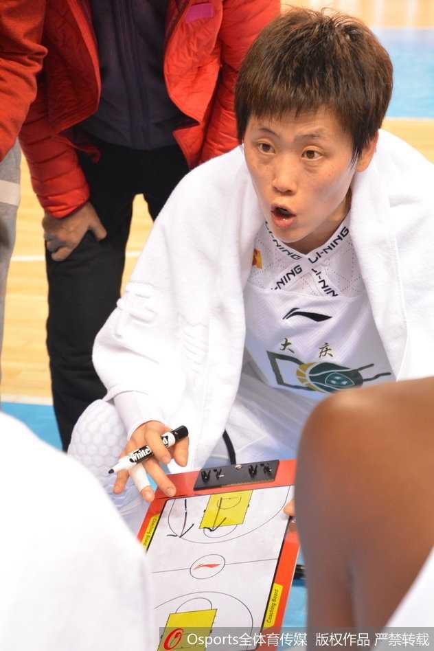 黑龙江队主教练半蹲在场边，手臂用力指向场内，脸部因大声指挥而涨得通红，眼神中透露出不容置疑的坚决，身后的助教也紧张地盯着场内变化。