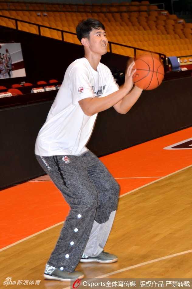 助教鞠维松正全神贯注地指点着张春军的投篮手型，篮筐之下，是打磨技术的宁静角落。