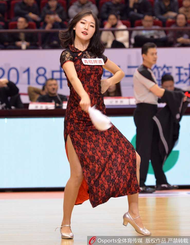 特写镜头下，一位啦啦队员回眸一笑，精致的妆容与复古旗袍的盘扣细节相得益彰，背景是模糊的看台人海，迷人风采令人过目难忘。